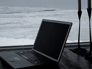 Laptop lama terbuka di meja dekat jendela