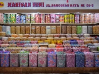 Ilustrasi rak toko jajanan di Jakarta penuh toples permen dan manisan warna-warni
