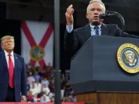 Robert F Kennedy Jr berpidato di podium kepresidenan sementara Donald Trump berdiri di belakangnya