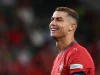 Cristiano Ronaldo tersenyum dengan seragam merah tim nasional Portugal