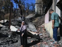 Sepasang warga memeriksa rumah yang rusak akibat kebakaran hutan di Jijel