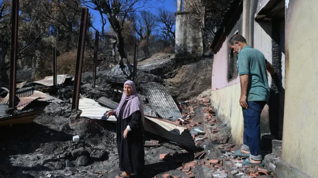 Sepasang warga memeriksa rumah yang rusak akibat kebakaran hutan di Jijel