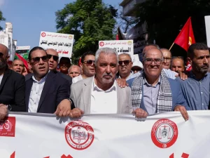 Pemimpin UGTT dan demonstran berbaris di belakang spanduk saat protes di Tunis