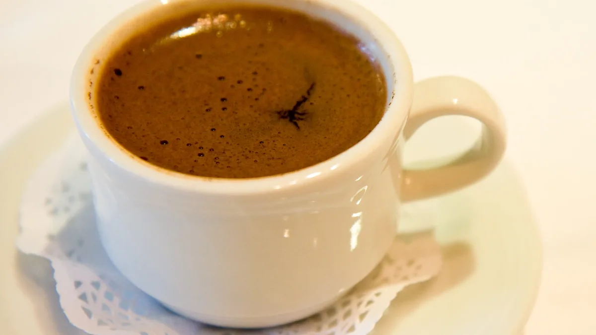 Ilustrasi: secangkir kopi Turki berbusa dalam cangkir putih di atas tatakan beralas kertas renda