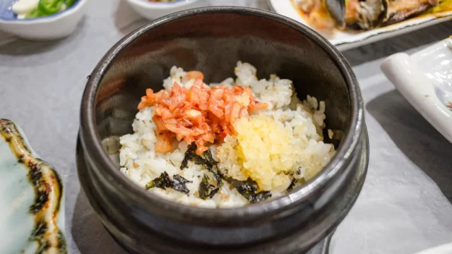 Ilustrasi semangkuk nasi putih dengan kimchi dan rumput laut serta lauk pendamping Korea