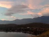 Ilustrasi kampung di tepi Danau Sentani saat senja berlatar pegunungan, Papua