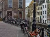 Ilustrasi deretan sepeda terparkir di tepi kanal dengan rumah bata khas Belanda di Utrecht