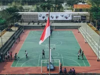 Ilustrasi siswa bermain basket di lapangan sekolah berbendera Merah Putih, Jawa Tengah, dari udara