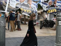Seorang perempuan berjalan melewati spanduk kampanye bergambar Benjamin Netanyahu dan Donald Trump