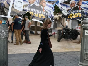Seorang perempuan berjalan melewati spanduk kampanye bergambar Benjamin Netanyahu dan Donald Trump