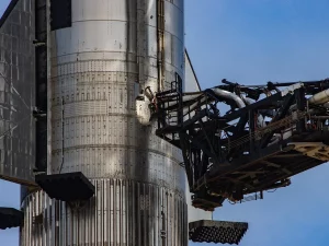 Roket Starship milik SpaceX berdiri di samping lengan menara peluncuran di Starbase