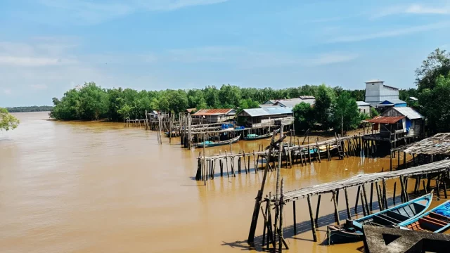 Ilustrasi rumah panggung, titian kayu, dan perahu nelayan di tepi Sungai Parit V, Kuala Tungkal, Jambi
