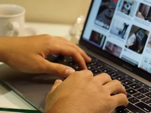 Ilustrasi dua tangan mengetik di papan ketik laptop di atas meja