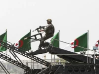 Tentara Aljazair bersenjata di atas kendaraan militer dengan deretan bendera Aljazair