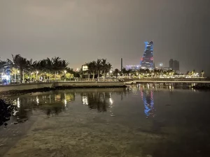Ilustrasi tepi laut Corniche Jeddah, Arab Saudi, dengan deretan pohon palem berlampu malam hari