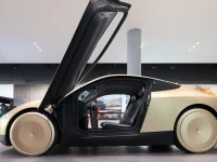 Mobil otonom Tesla Cybercab berwarna keemasan dengan pintu terbuka ke atas di ruang pamer