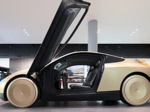 Mobil otonom Tesla Cybercab berwarna keemasan dengan pintu terbuka ke atas di ruang pamer