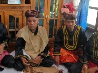 Empat tetua adat berbaju hitam bersulam emas duduk bersila saat Kenduri Sko