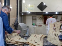 Ilustrasi pembeli mengambil lembaran roti sangak yang baru matang di toko roti Tehran, Iran