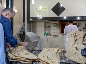 Ilustrasi pembeli mengambil lembaran roti sangak yang baru matang di toko roti Tehran, Iran