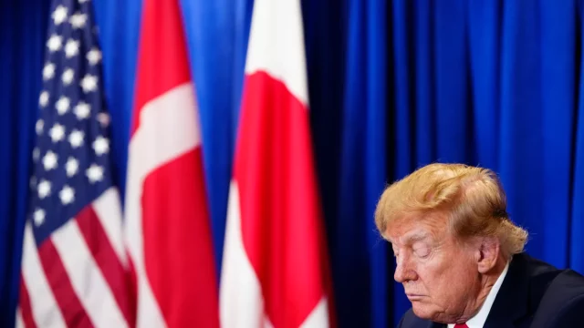 Donald Trump menunduk di depan bendera AS, Denmark, dan Greenland saat penandatanganan