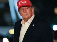 Presiden AS Donald Trump bertopi merah bertuliskan USA saat tiba di Gedung Putih