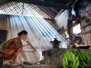 Perempuan Osing meniup tungku kayu dengan semprong bambu di dapur tradisional Kemiren, Banyuwangi