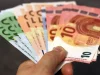 Tangan memegang lembaran uang kertas euro