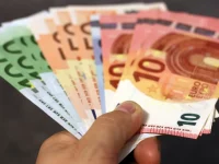 Tangan memegang lembaran uang kertas euro