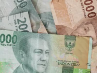 Uang kertas rupiah pecahan dua puluh ribu dan lima puluh ribu tergeletak di atas meja kayu