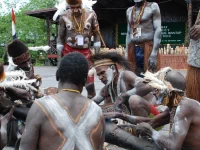 Ilustrasi sekelompok laki-laki Asmat berhias cat tubuh putih berjongkok mengelilingi batang kayu di Papua