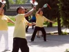 Tiga lansia berkaus kuning bermain bola raket tai chi di Taman Tiantan, Beijing, Tiongkok