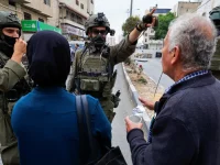 Warga Palestina berdebat dengan tentara Israel bersenjata di sebuah jalan di Hebron