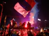 Kerumunan warga mengibarkan bendera Serbia dan menyalakan suar pada malam hari