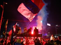 Kerumunan warga mengibarkan bendera Serbia dan menyalakan suar pada malam hari