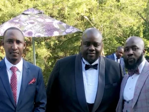 Wicknell Chivayo berfoto bersama dua pria berjas di taman resepsi di Harare