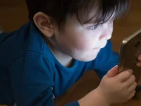 Anak laki-laki menatap layar ponsel pintar