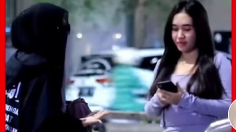 Seorang wanita bercadar memaksa pengunjung wanita yang ada di tengah keramaian dan tampak berpakaian seksi agar mau menutup auratnya.