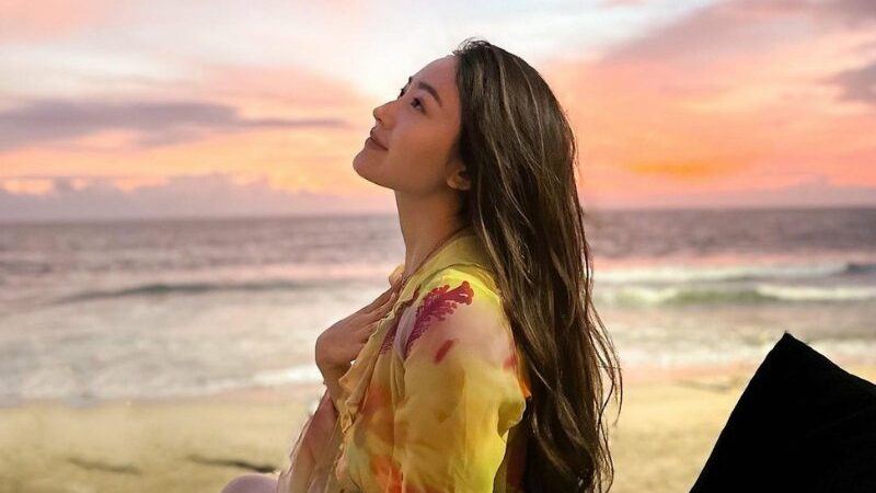 Cekricek.id – Natasha Wilona tampil cantik memukau saat duduk santai di tepi pantai sambil menikmati sunset. Warna jingga yang menjadi latar tempatnya berada sukses membuat penampakan wajahnya menjadi lebih berseri dan semakin menarik perhatian banyak orang untuk melihat ke arahnya.