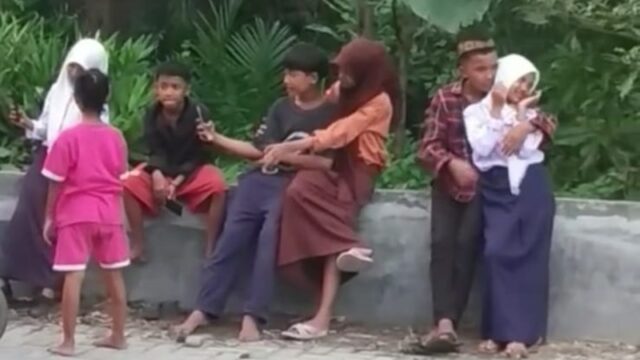 Empat pasang bocah di bawah umur saling bermesraan di tepi jalan sembari bermain ponsel, bahkan ada yang nekat membuka hijabnya.