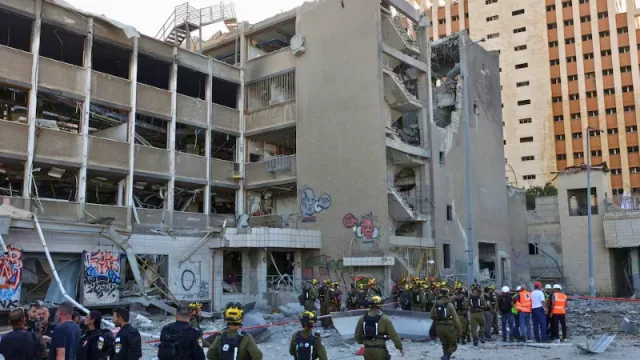 Petugas keamanan dan puing-puing bangunan rusak akibat serangan di Haifa, Israel, menunjukkan dampak konflik Timur Tengah